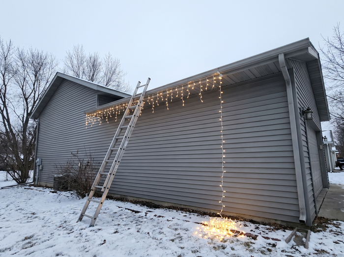 A ladder against the wall with the curtain half clipped to the gutter